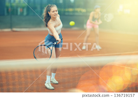 Two young women playing doubles tennis Two young women playing doubles tennis 136719157