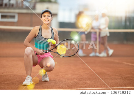 Young woman posing on tennis court 136719212