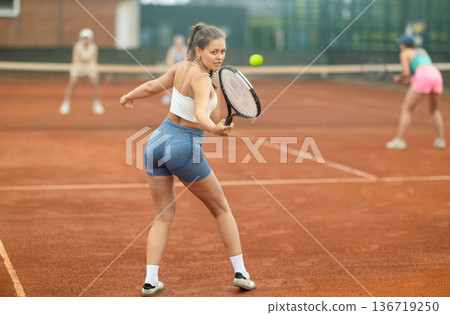 Two young women playing tennis against elderly women 136719250