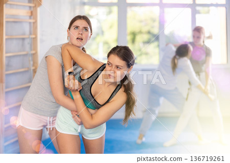 Adolescent girl practicing basic techniques in sparring during self-defense training Adolescent girl practicing basic techniques in sparring during self-defense training 136719261