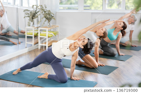 Hispanic woman practicing Gate Pose during group yoga session Hispanic woman practicing Gate Pose during group yoga session 136719300
