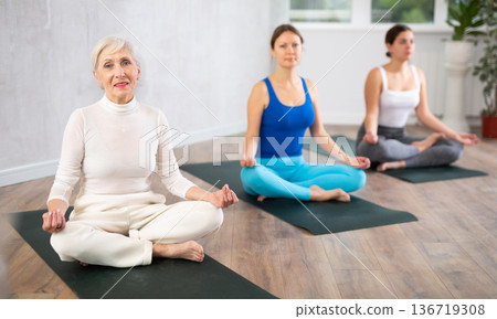 Senior woman sitting in Padmasana yoga position with hands in mudra 136719308