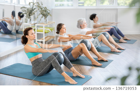 Adult woman doing pilates with soft ball in group Adult woman doing pilates with soft ball in group 136719353