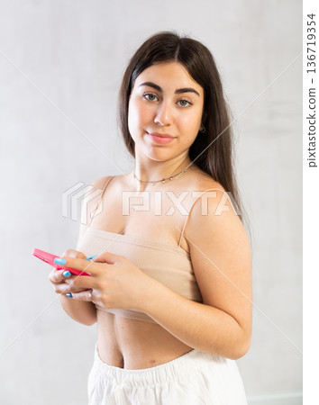 Young woman reading message on phone in studio 136719354