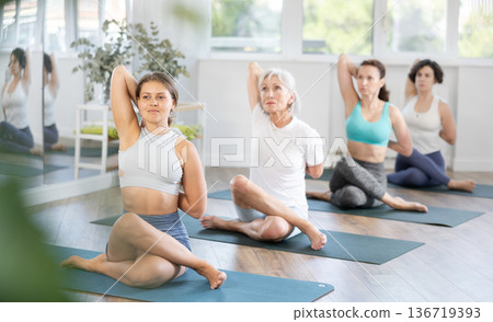 Young woman doing yoga in group in studio Young woman doing yoga in group in studio 136719393