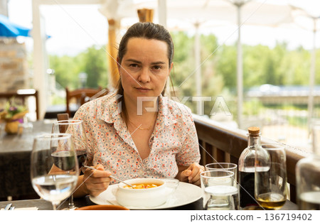 Portrait of woman spending time on terrace of restaurant and eating traditional spanish gazpacho 136719402