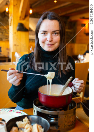 Woman eating tradicional Swiss dish - fondue Woman eating tradicional Swiss dish - fondue 136719409