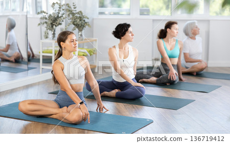 Young woman doing yoga in group in studio Young woman doing yoga in group in studio 136719412