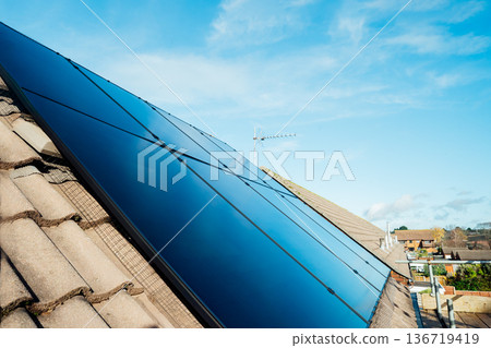 Close up solar power roof panel on Modern, energy-efficient house with blue sky background. Renewable eco Energy. Concept of economy and profit from selling excess electricity. Smart energy management Close up solar power roof panel on Modern, energy-efficient house with blue sky background. Renewable eco Energy. Concept of economy and profit from selling excess electricity. Smart energy management 136719419
