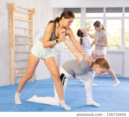 Adolescent girl applying armlock in simulated sparring at self-defense classes Adolescent girl applying armlock in simulated sparring at self-defense classes 136719448