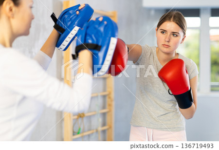 Teen girl in punch mitts boxing Teen girl in punch mitts boxing 136719493