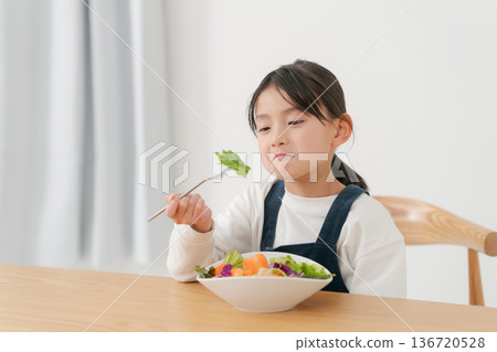 A girl eating vegetables she doesn't like A girl eating vegetables she doesn't like 136720528
