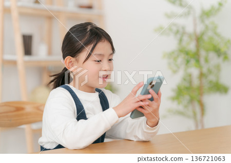 Elementary school girl looking at smartphone 136721063