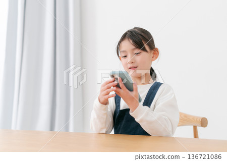 玩智慧型手機的小學生女孩 136721086