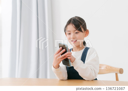Elementary school girl playing with smartphone Elementary school girl playing with smartphone 136721087