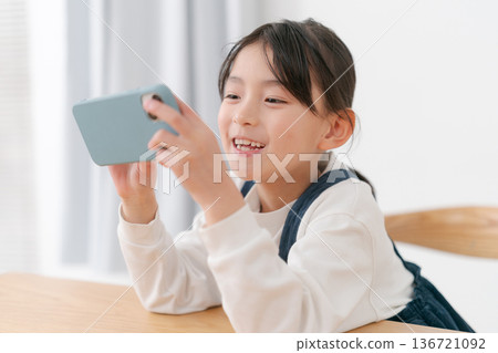 玩智慧型手機的小學生女孩 136721092
