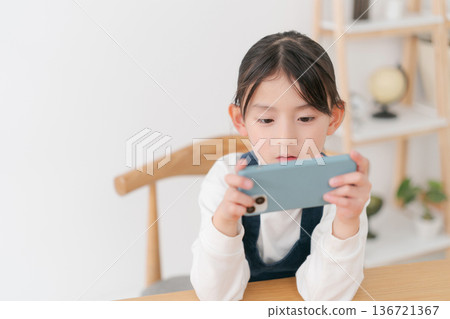 Elementary school girl looking at smartphone Elementary school girl looking at smartphone 136721367