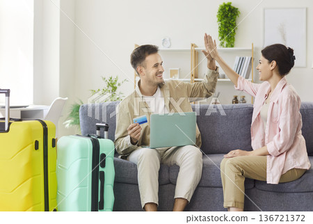 Couple high five after booking vacation online with laptop and credit card at home 136721372