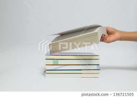 A woman's hand lifting a stack of books 136721505