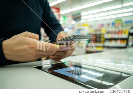 一位日本人正在使用智慧型手機上的二維碼支付，這展現了生成式人工智慧在智慧型手機上的應用。 136721798