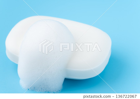 A single white bar of soap and bubbles on a light blue background A single white bar of soap and bubbles on a light blue background 136722067