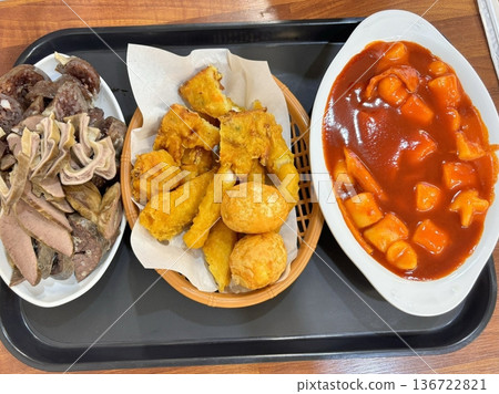 Bunsik, a popular Korean street food, features comforting and savory dishes like tteokbokki (spicy rice cakes), odeng (fish cake skewers), and kimbap (seaweed rice rolls). Perfect for quick meals. 136722821