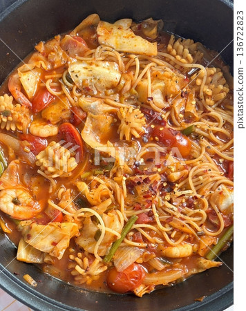 A hearty bowl of Budaejjigae (Korean Army Stew), filled with sausage, tofu, kimchi, and noodles in a spicy broth. This flavorful dish brings warmth and comfort, perfect for sharing. 136722823