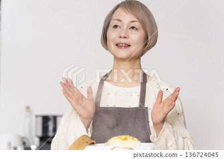 A senior woman steaming sweet potato buns in a bamboo steamer in the kitchen 136724045