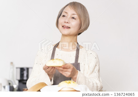 A senior woman steaming sweet potato buns in a bamboo steamer in the kitchen A senior woman steaming sweet potato buns in a bamboo steamer in the kitchen 136724065
