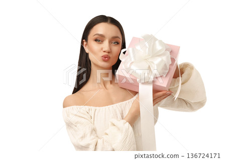 Young woman presents a pink gift box joyfully, isolated on white, PNG 136724171