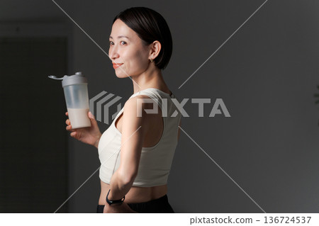 身穿運動服的女子手持蛋白質 身穿運動服的女子手持蛋白質 136724537