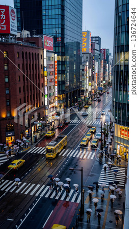 Busy City Street in Tokyo at Dusk with Numerous Pedestrians and Traffic 136724644