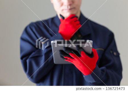 A middle-aged male businessman in work clothes looking at a tablet and worrying 136725473