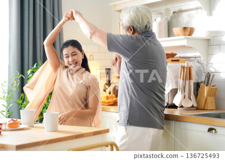 Asia happy older senior elderly couple dance waltz after cooking at kitchen room. Asia happy older senior elderly couple dance waltz after cooking at kitchen room. 136725493
