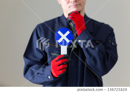 A middle-aged male businessman in work clothes worried about holding a plate with a "X" on it 136725829