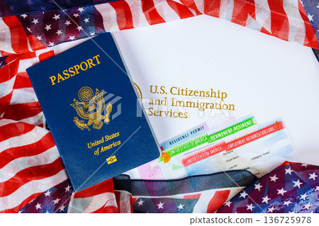 U.S. passport is placed next to immigration documents fabric with American flag on table. 136725978