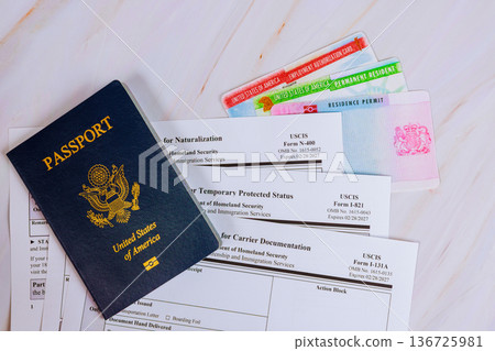 American passport, several immigration N-400, I-821, I-131A, forms are on table showing process of obtaining residency in USA. 136725981
