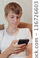 Teen boy is looking at his phone. boy using a phone. concept of scrolling, gadget addiction 136726603