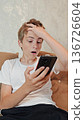 guy is looking at phone and feeling surprised and excited. guy shocked by message received wins online bets looking at mobile phone. 136726604
