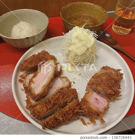 Crispy tonkatsu, a Japanese-style breaded and deep-fried pork cutlet, served with shredded cabbage and drizzled with savory sauce. A delightful balance of crunchy texture and juicy meat. 136726941