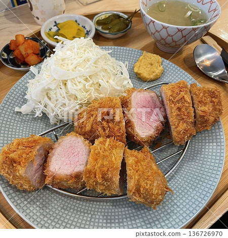 Crispy tonkatsu, a Japanese-style breaded and deep-fried pork cutlet, served with shredded cabbage and drizzled with savory sauce. A delightful balance of crunchy texture and juicy meat. Crispy tonkatsu, a Japanese-style breaded and deep-fried pork cutlet, served with shredded cabbage and drizzled with savory sauce. A delightful balance of crunchy texture and juicy meat. 136726970