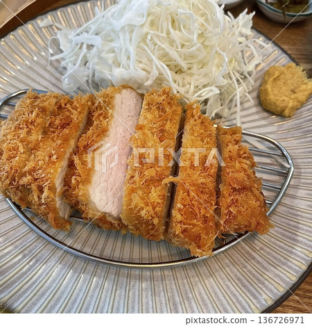 Crispy tonkatsu, a Japanese-style breaded and deep-fried pork cutlet, served with shredded cabbage and drizzled with savory sauce. A delightful balance of crunchy texture and juicy meat. Crispy tonkatsu, a Japanese-style breaded and deep-fried pork cutlet, served with shredded cabbage and drizzled with savory sauce. A delightful balance of crunchy texture and juicy meat. 136726971