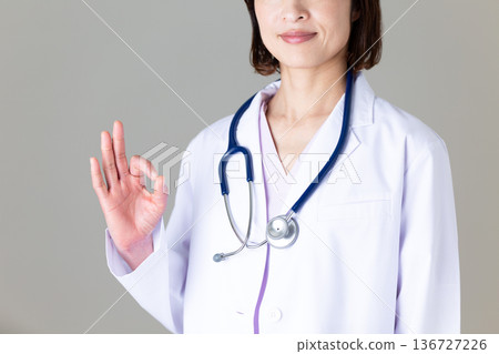 一位身穿白大褂的中年女醫生做了一個圓圈手勢 136727226