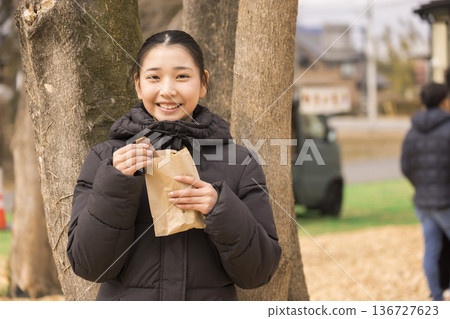 笑容滿面的女孩從袋子裡拿出烤地瓜。 136727623