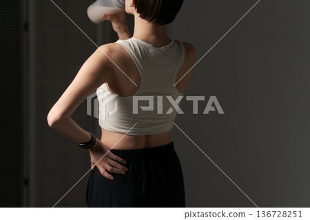 一位女性背對著鏡頭喝蛋白質飲料 136728251