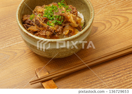 Japanese food image of beef bowl and chopsticks placed on a wood-grain table Japanese food image of beef bowl and chopsticks placed on a wood-grain table 136729653