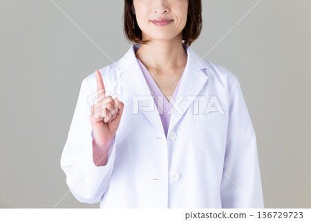 一位身穿白大褂的中年女醫生舉起她的食指 136729723