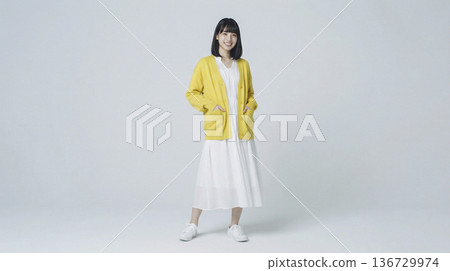 一位面帶微笑的日本女子穿著黃色開襟衫和白色連身裙。 136729974
