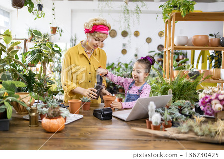 A woman and a young girl are potting plants together, creating a heartwarming scene of family and nature 136730425