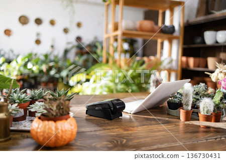 This image captures the inviting atmosphere of a local plant shop, showcasing a variety of greenery and a workspace This image captures the inviting atmosphere of a local plant shop, showcasing a variety of greenery and a workspace 136730431